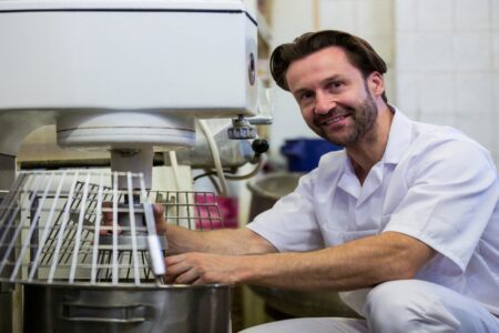 Un pâtissier heureux d'utiliser sa machine à pétrir