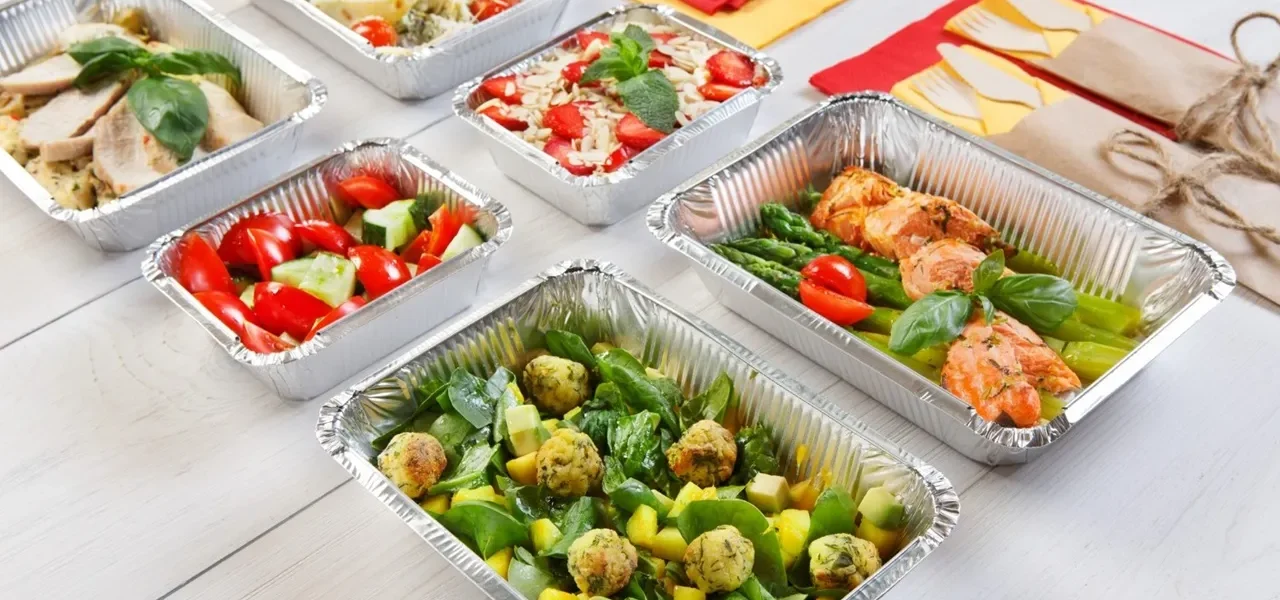 Plats en aluminium jetables disposés sur un buffet chaud pour un repas convivial