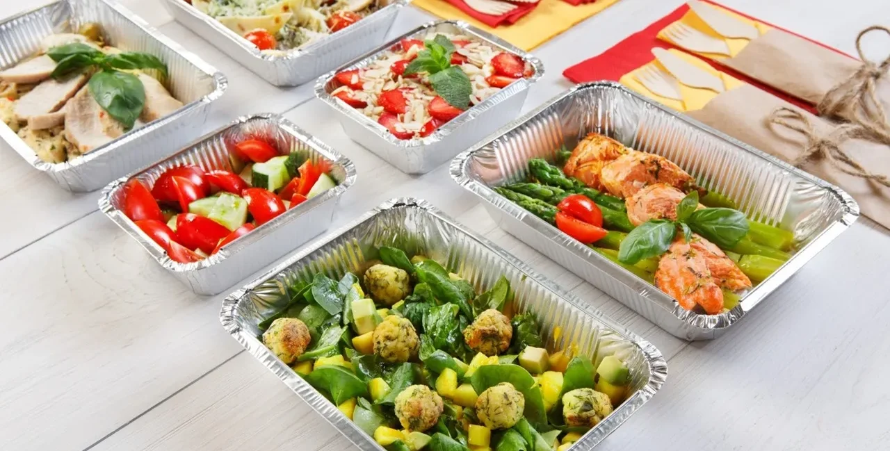 Plats en aluminium jetables disposés sur un buffet chaud pour un repas convivial
