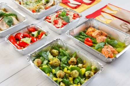 Plats en aluminium jetables disposés sur un buffet chaud pour un repas convivial